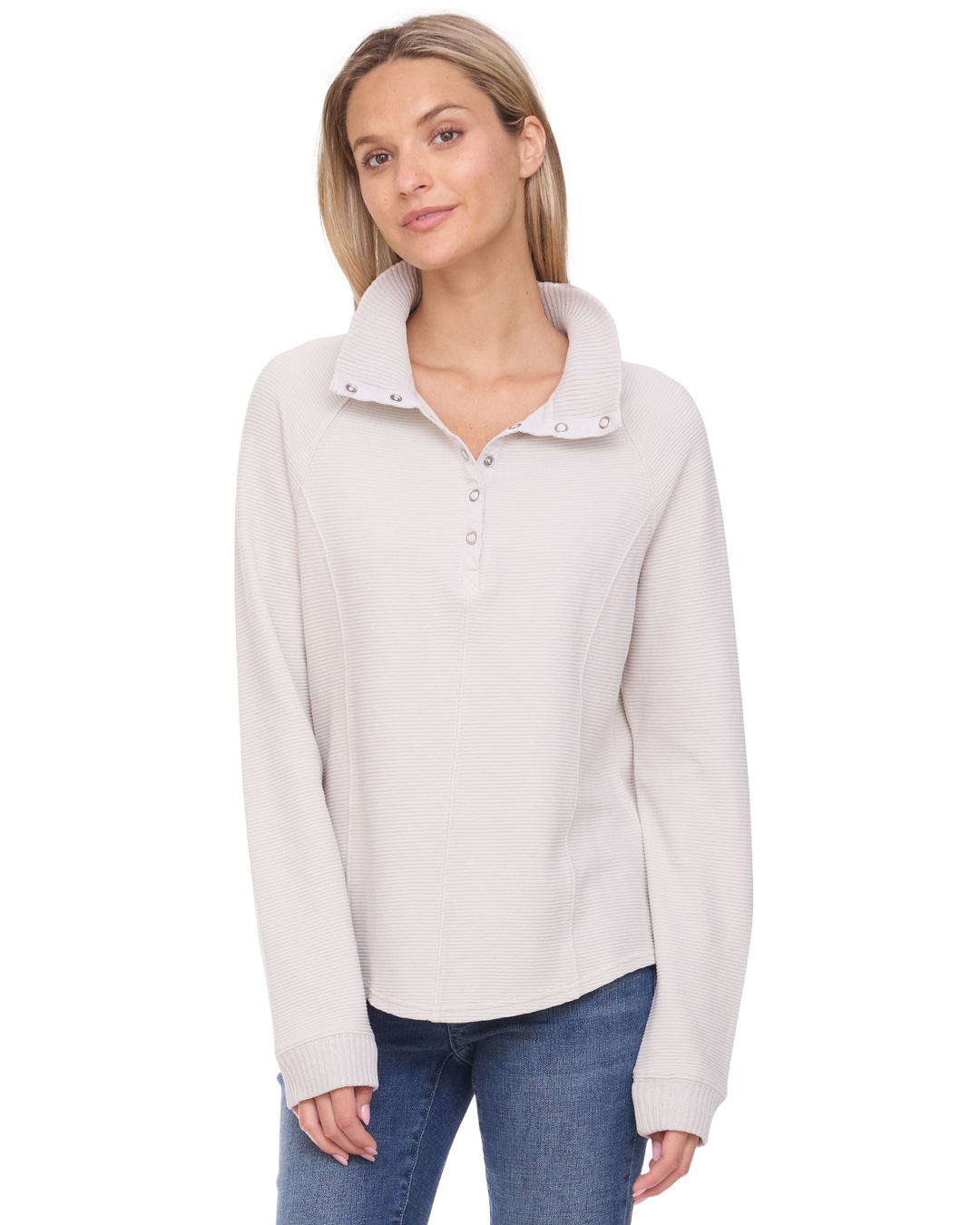 A woman wearing a light beige long-sleeve quarter-placket polo shirt with a textured waffle knit, paired with blue jeans, against a plain white background.