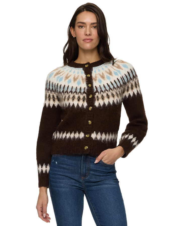 A woman modeling a brown button-front knit cardigan with a cream, beige, and light blue Fair Isle pattern across the yoke and sleeves, paired with blue jeans against a plain white background.