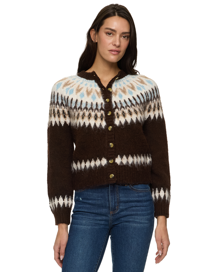 A woman modeling a brown knit button-up cardigan with a Fair Isle pattern in cream, light blue, and brown, paired with blue jeans against a plain white background.